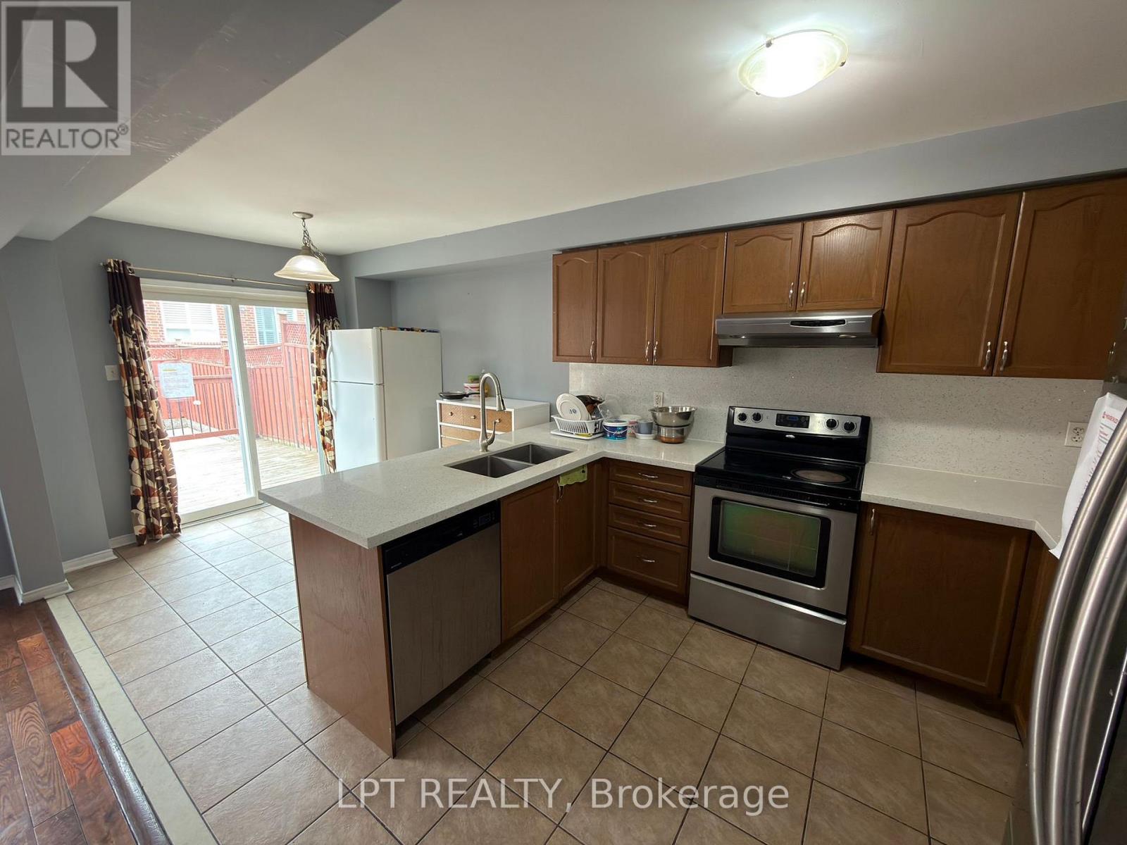 A kitchen with brown cabinets and a stainless steel refrigerator.