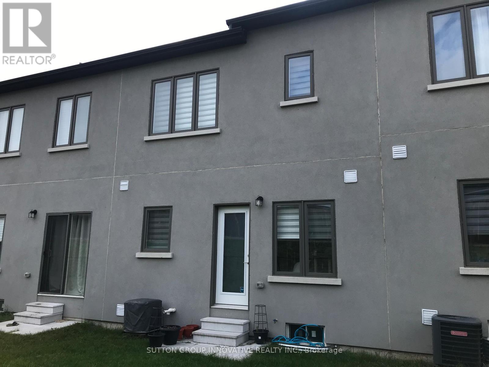 A grey building with a white door and windows.