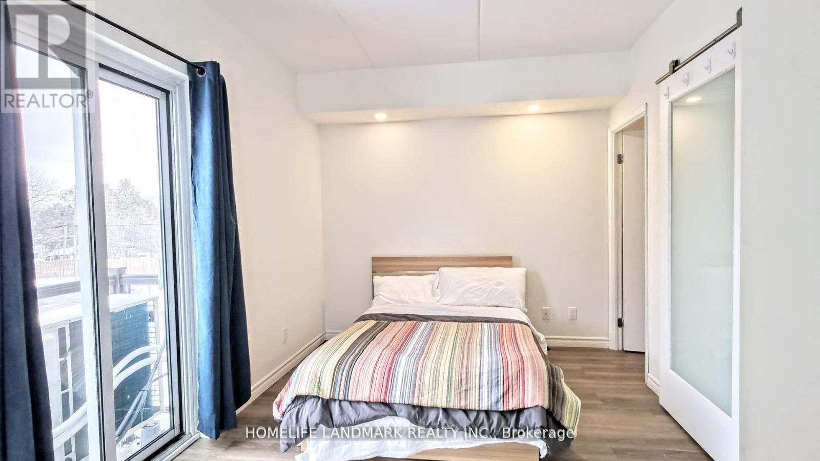 A bedroom with a striped bedspread and a large window.