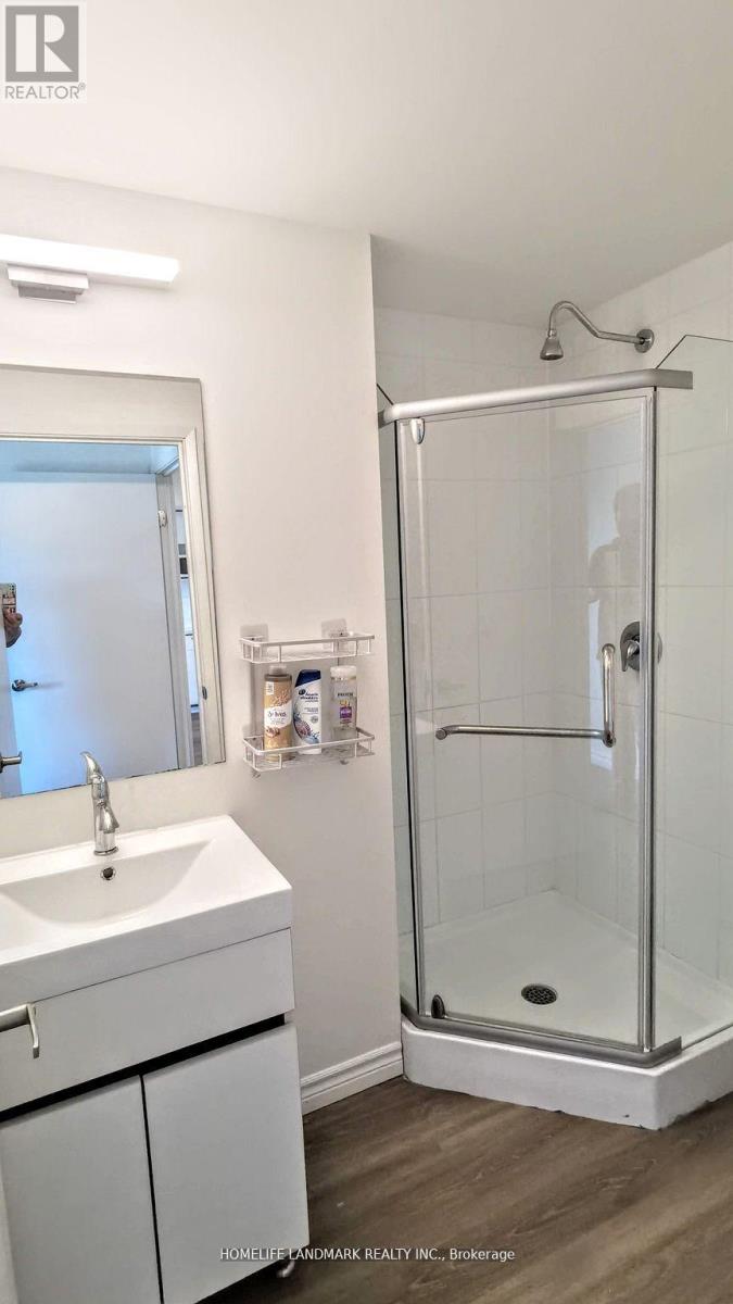 A white bathroom with a sink, mirror, and shower.
