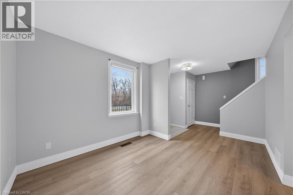 A spacious room with wooden flooring and a window with a view of trees.