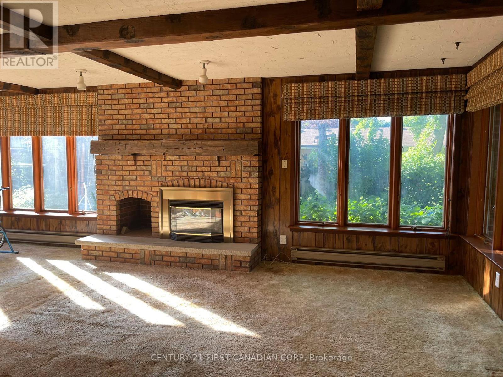 A room with a fireplace and a window with a view of trees.