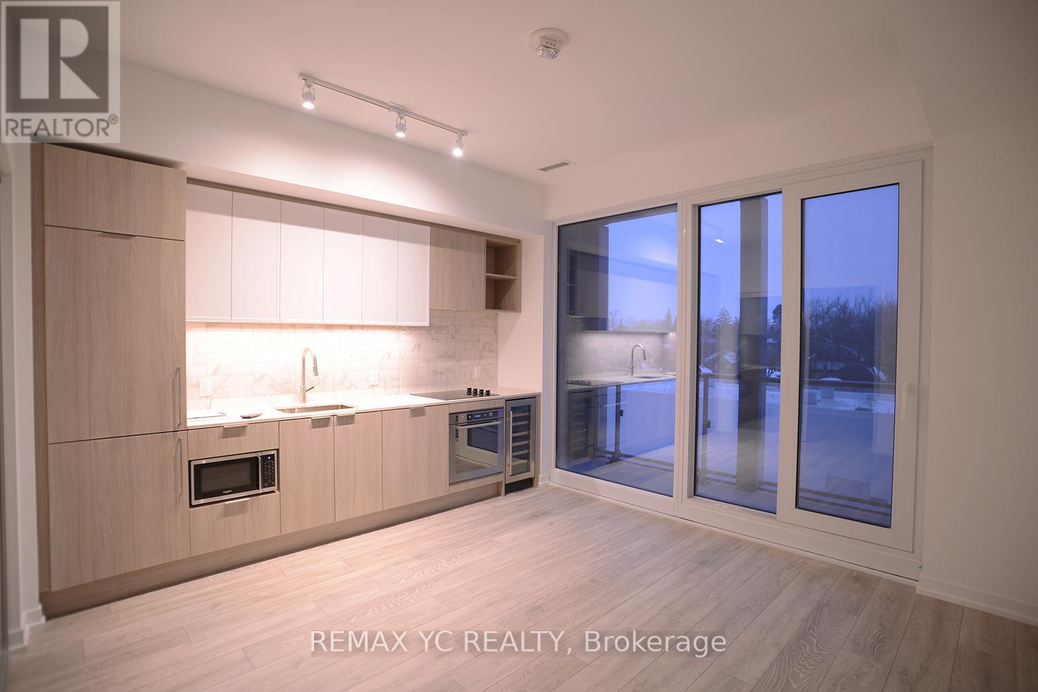 A modern kitchen with wooden cabinets and a large window.
