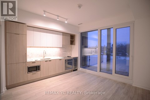 A modern kitchen with wooden cabinets and a large window.