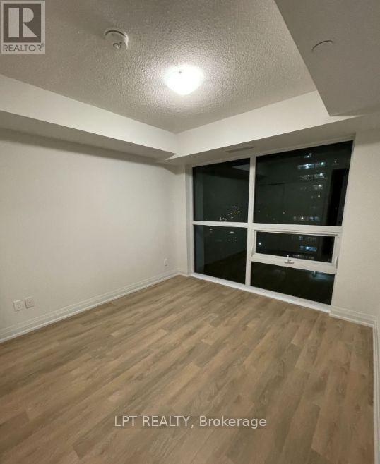 A room with wooden flooring and a window with blinds.