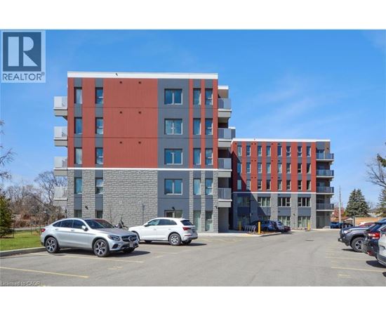 A modern multi-story building with a parking lot in front.