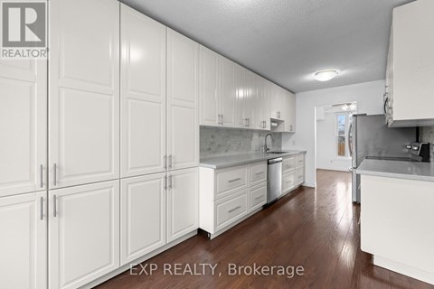 A kitchen with white cabinets and a wooden floor.