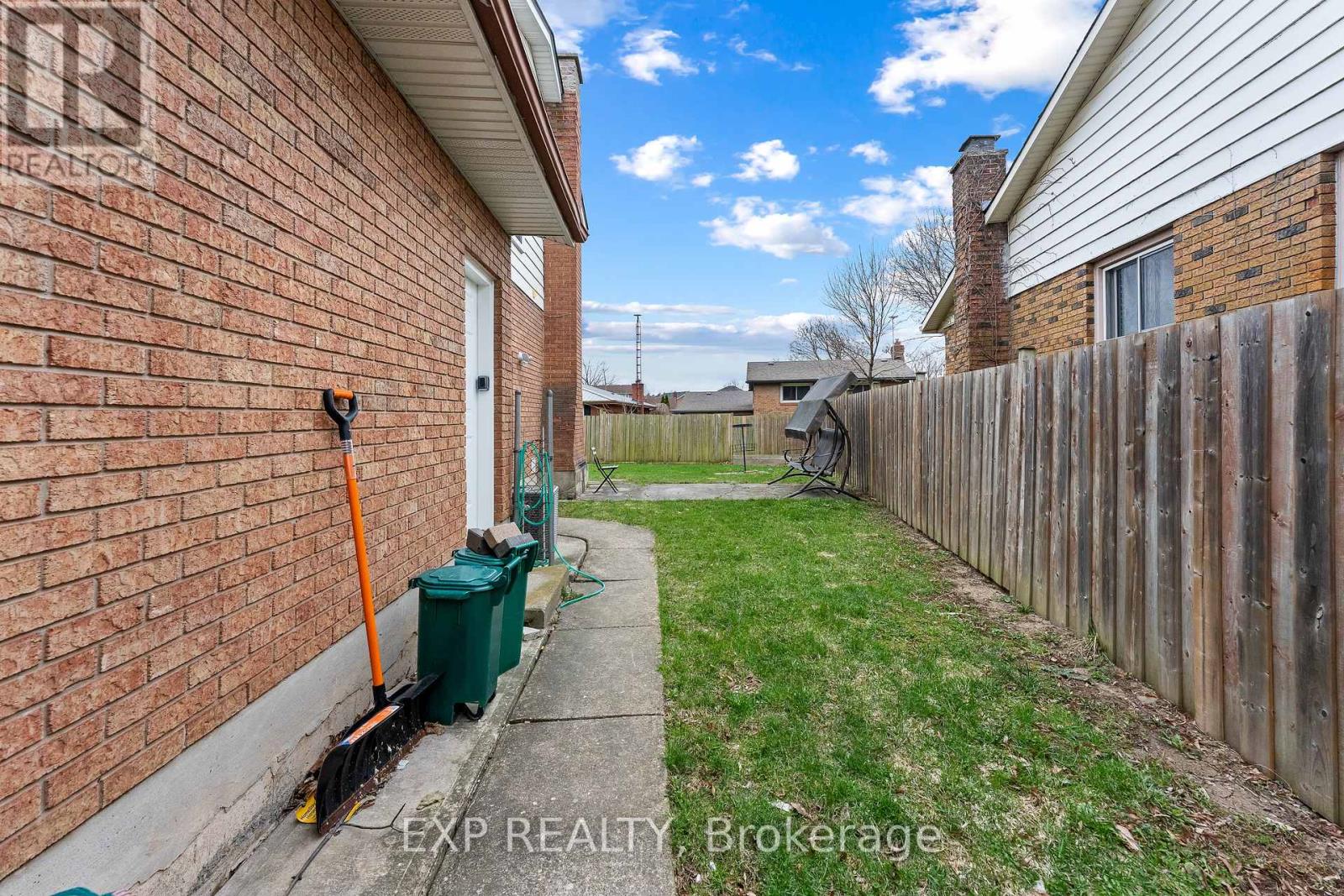 A brokerage sign is on the side of a brick house.