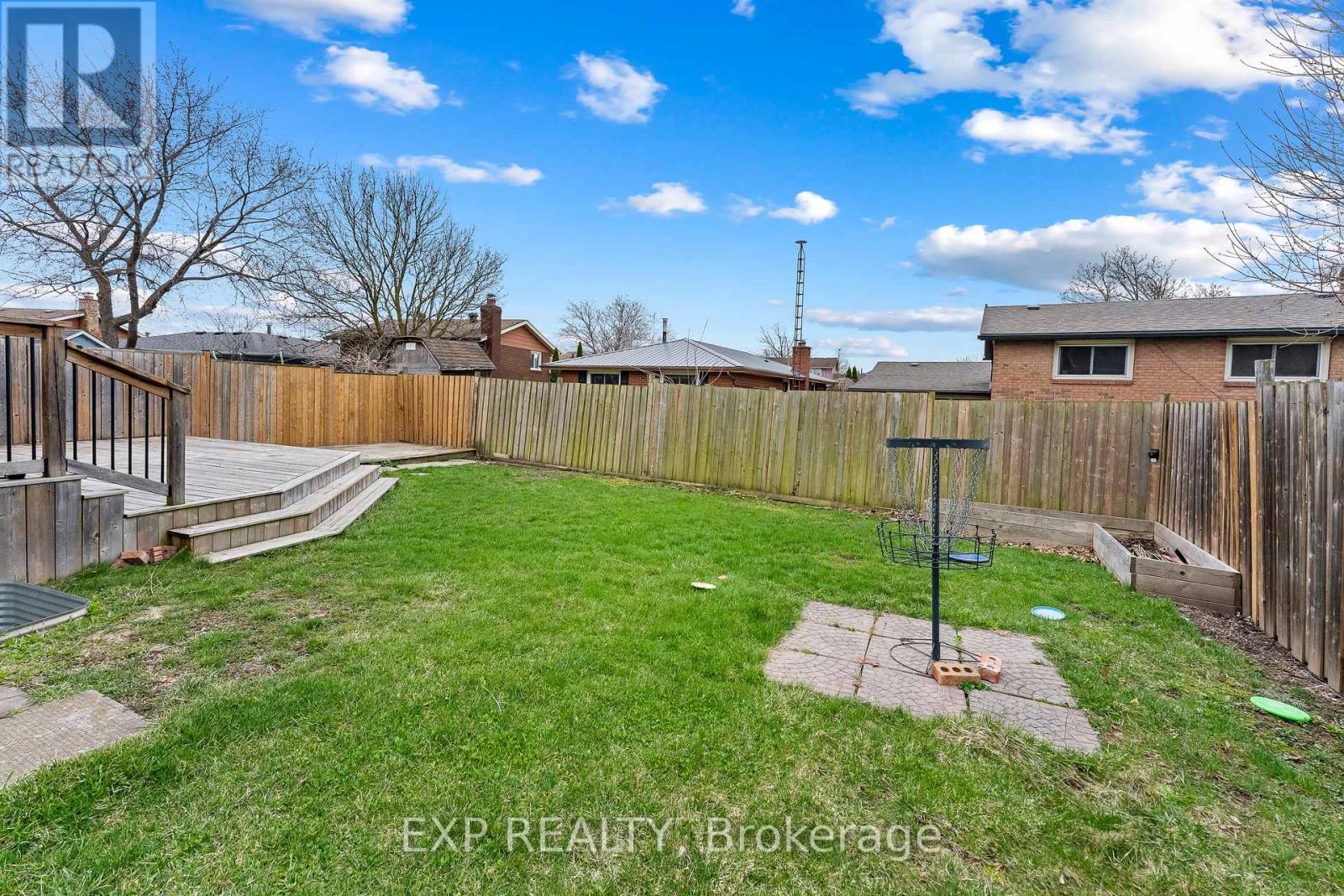 A backyard with a wooden fence and a small baseball field.