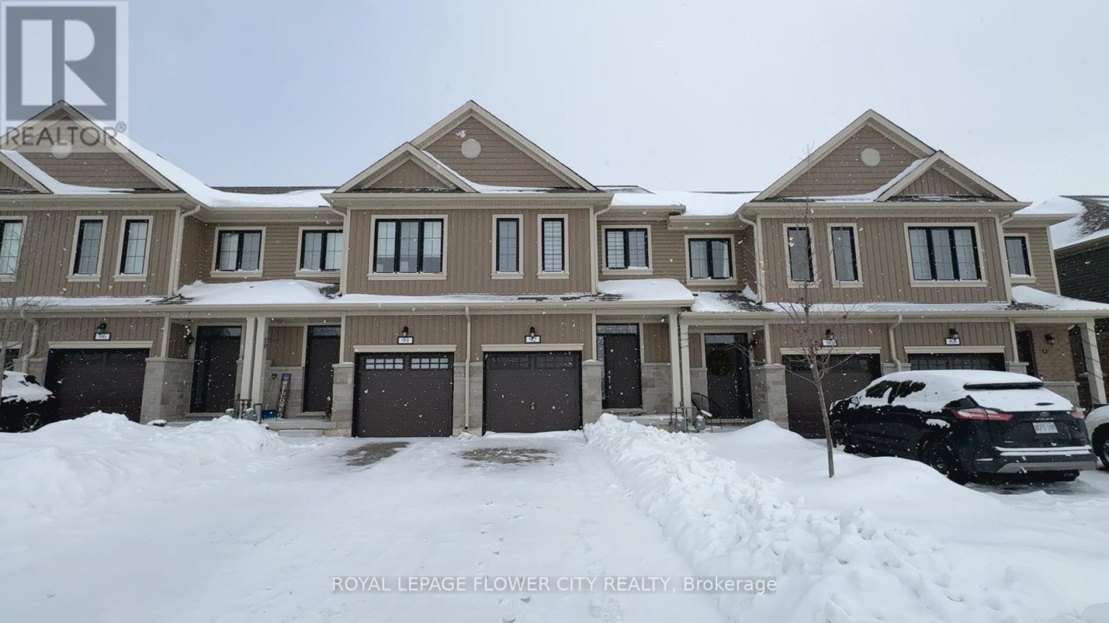 A row of houses with snow on the ground and parked cars.