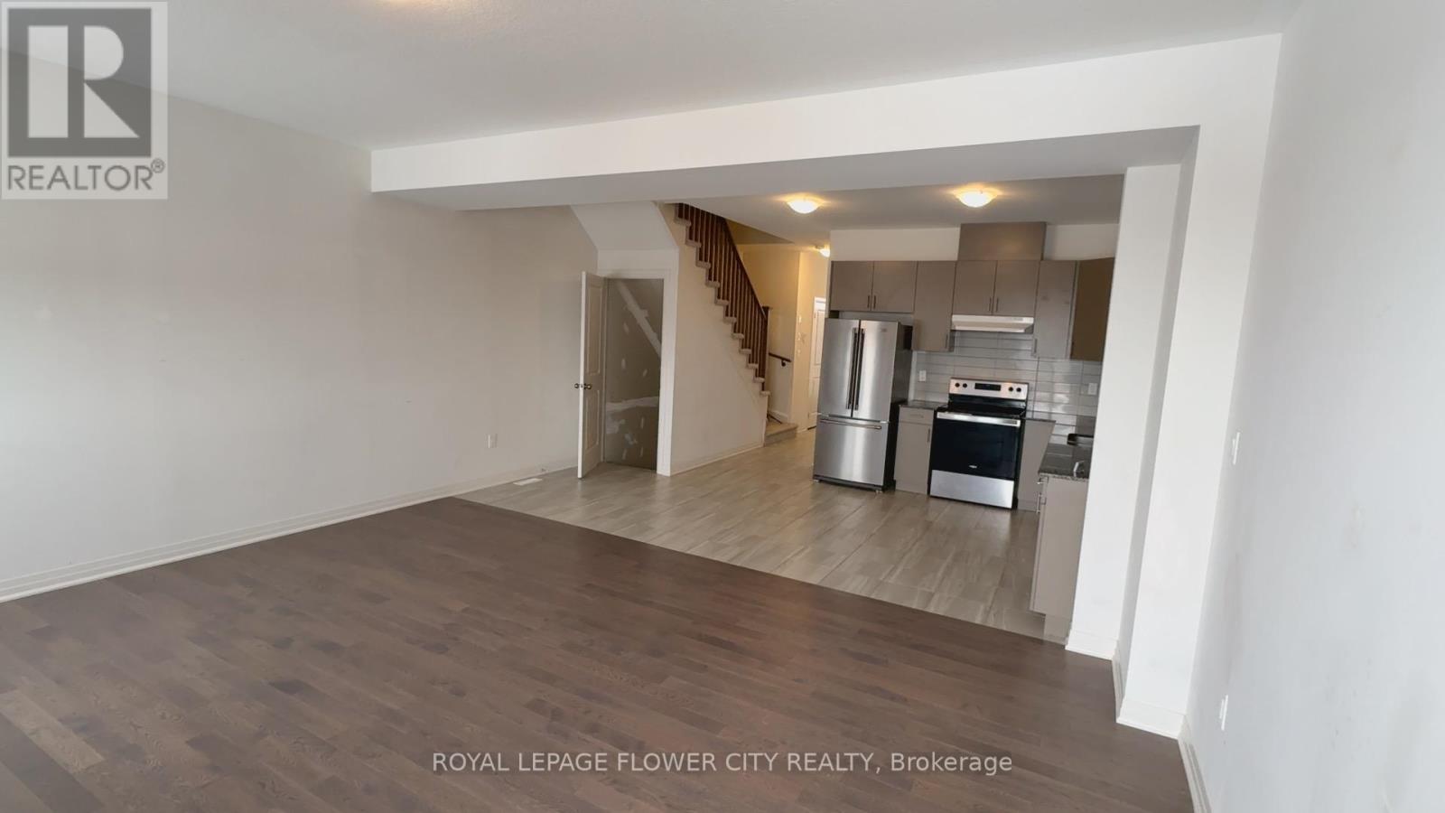A spacious room with wooden flooring and a staircase leading to another level.