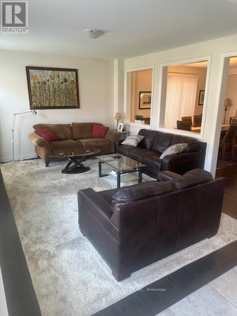 A living room with a brown couch and a painting on the wall.