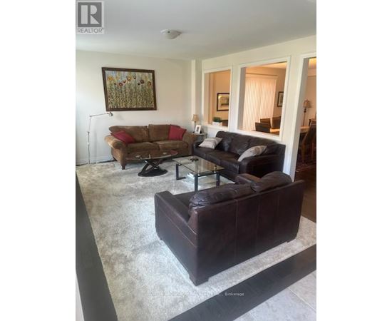 A living room with a brown couch and a painting on the wall.