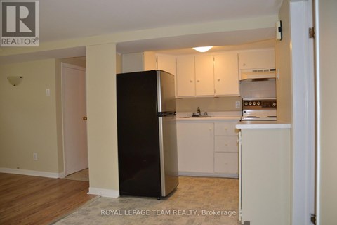 A kitchen with white cabinets and a black refrigerator.