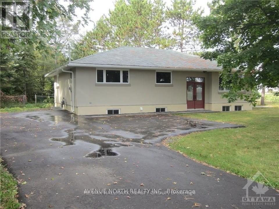 A house with a red door and a grey roof is surrounded by trees.