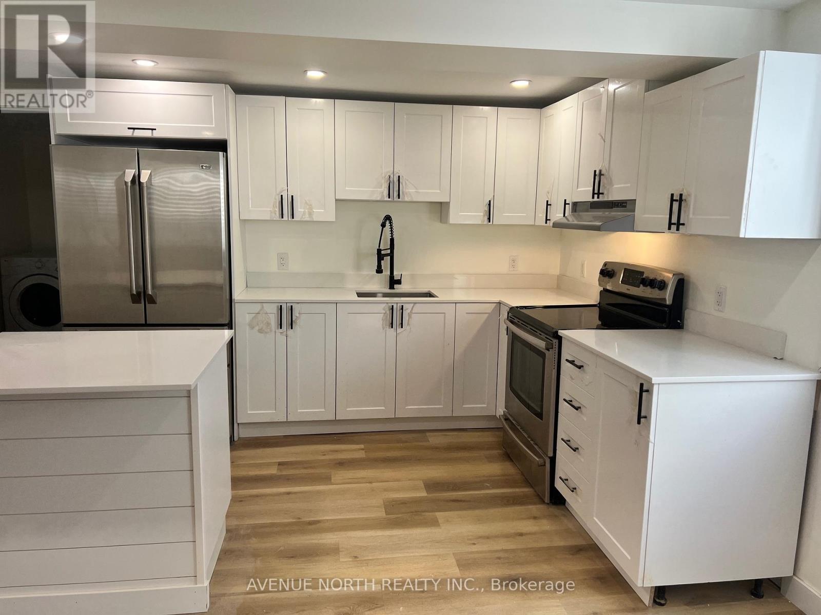 A kitchen with white cabinets and a stainless steel refrigerator.