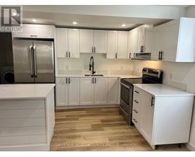 A kitchen with white cabinets and a stainless steel refrigerator.