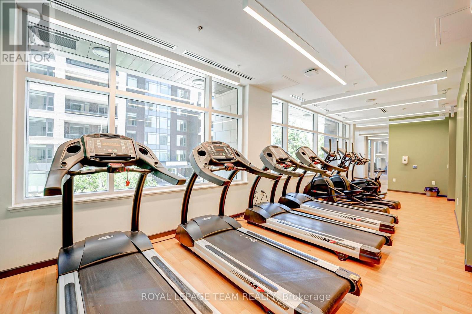 A gym with treadmills and a large window.