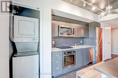 A modern kitchen with a stainless steel oven and a washing machine.