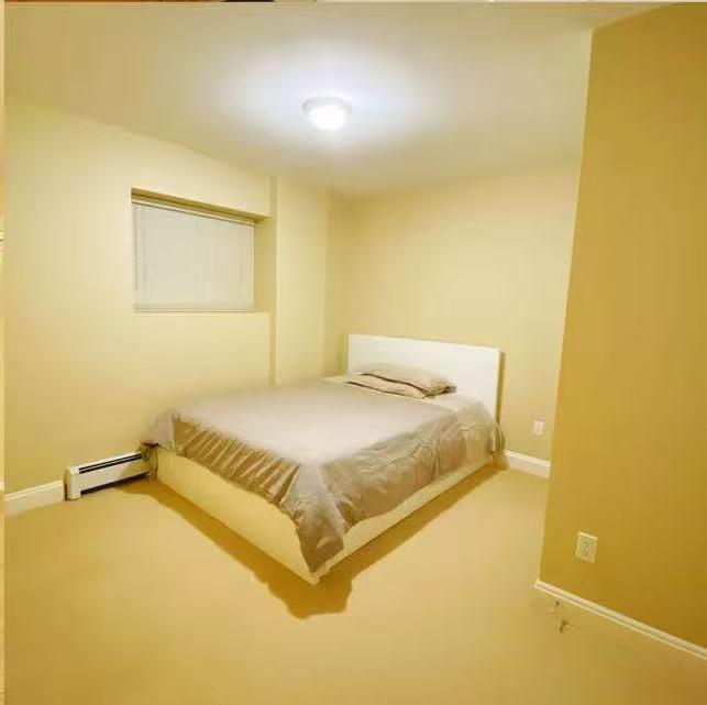 A bedroom with a bed, window, and light on the ceiling.