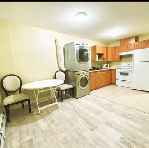 A kitchen with a white refrigerator, a white table and chairs, and a white washing machine.