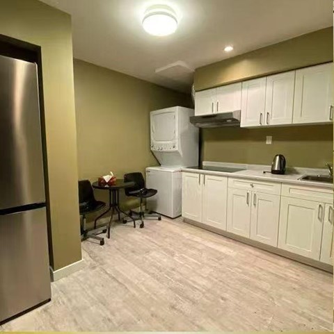A kitchen with a table and chairs and a refrigerator.