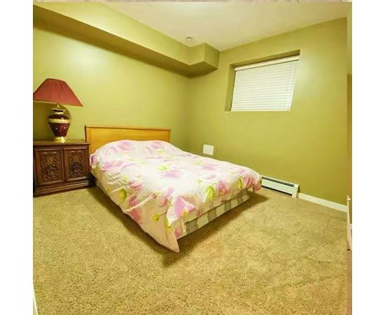 A bedroom with a bed, lamp, and carpet.