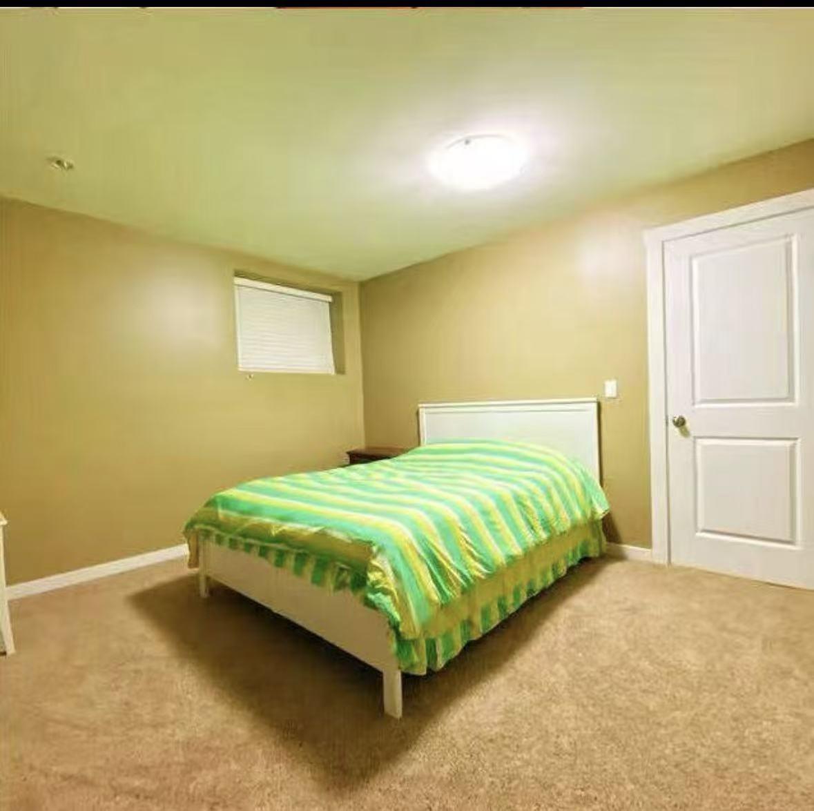 A bedroom with a bed and a carpeted floor.