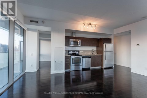 A spacious kitchen with dark wood floors and modern appliances.