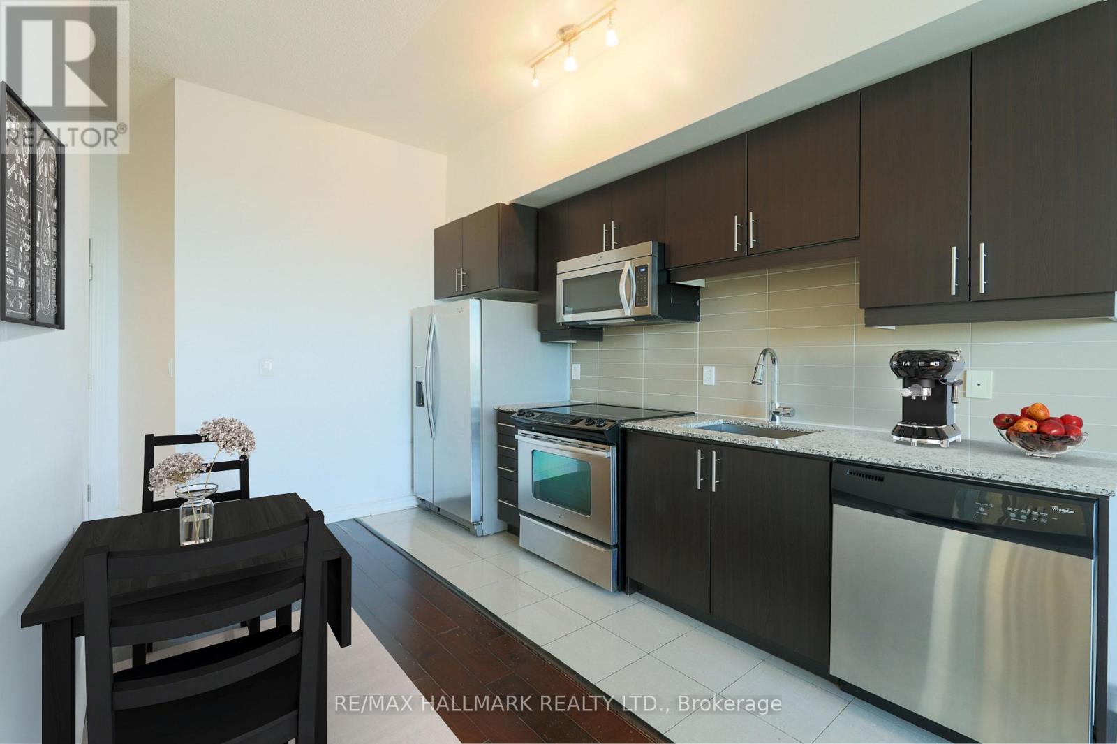 A kitchen with a black table and stainless steel appliances.