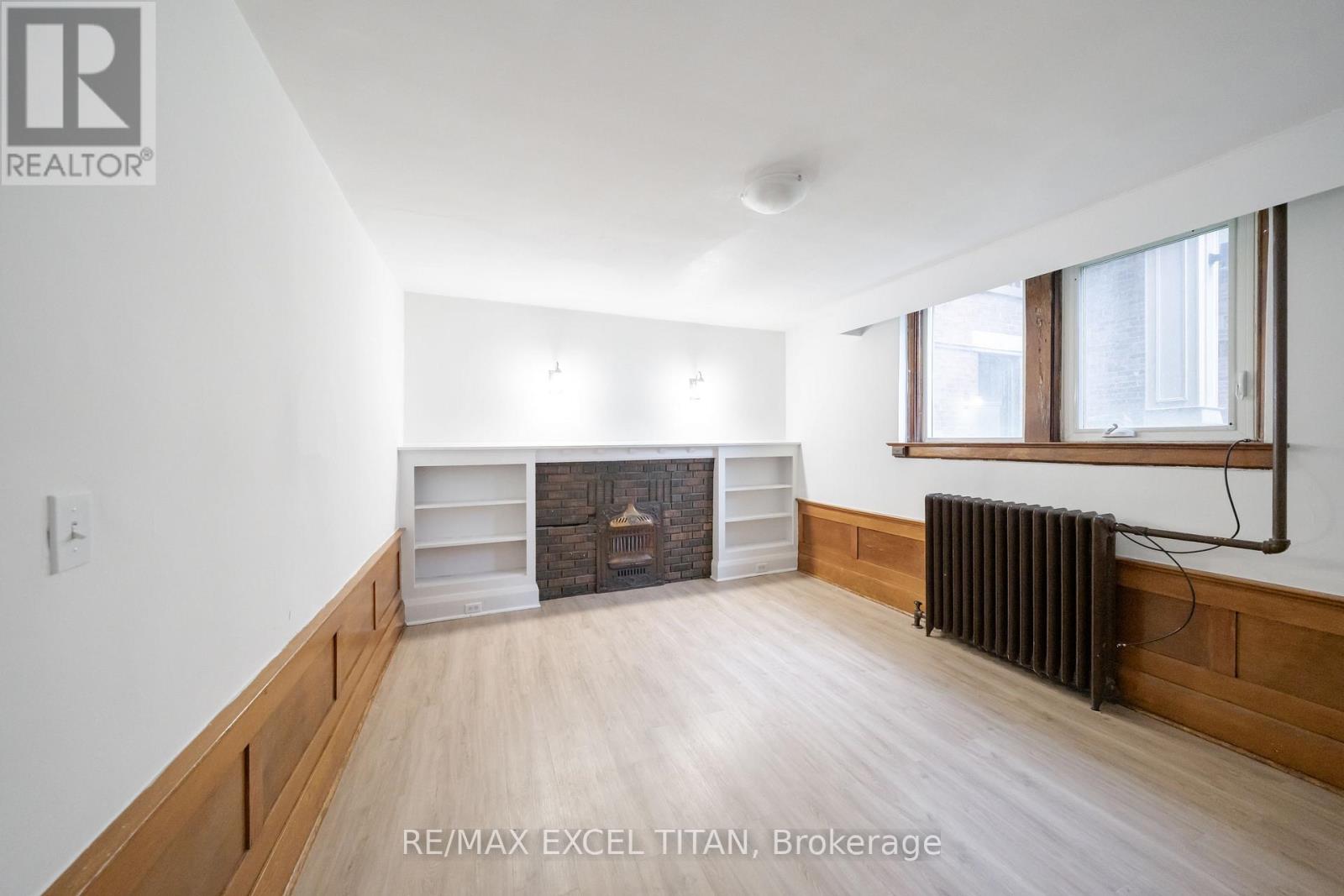 A large, empty room with a fireplace and a window.
