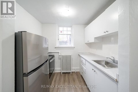 A white kitchen with a refrigerator, sink, and cabinets.