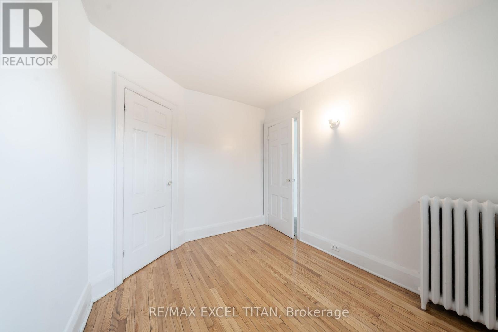 A white room with a wooden floor and a white radiator.