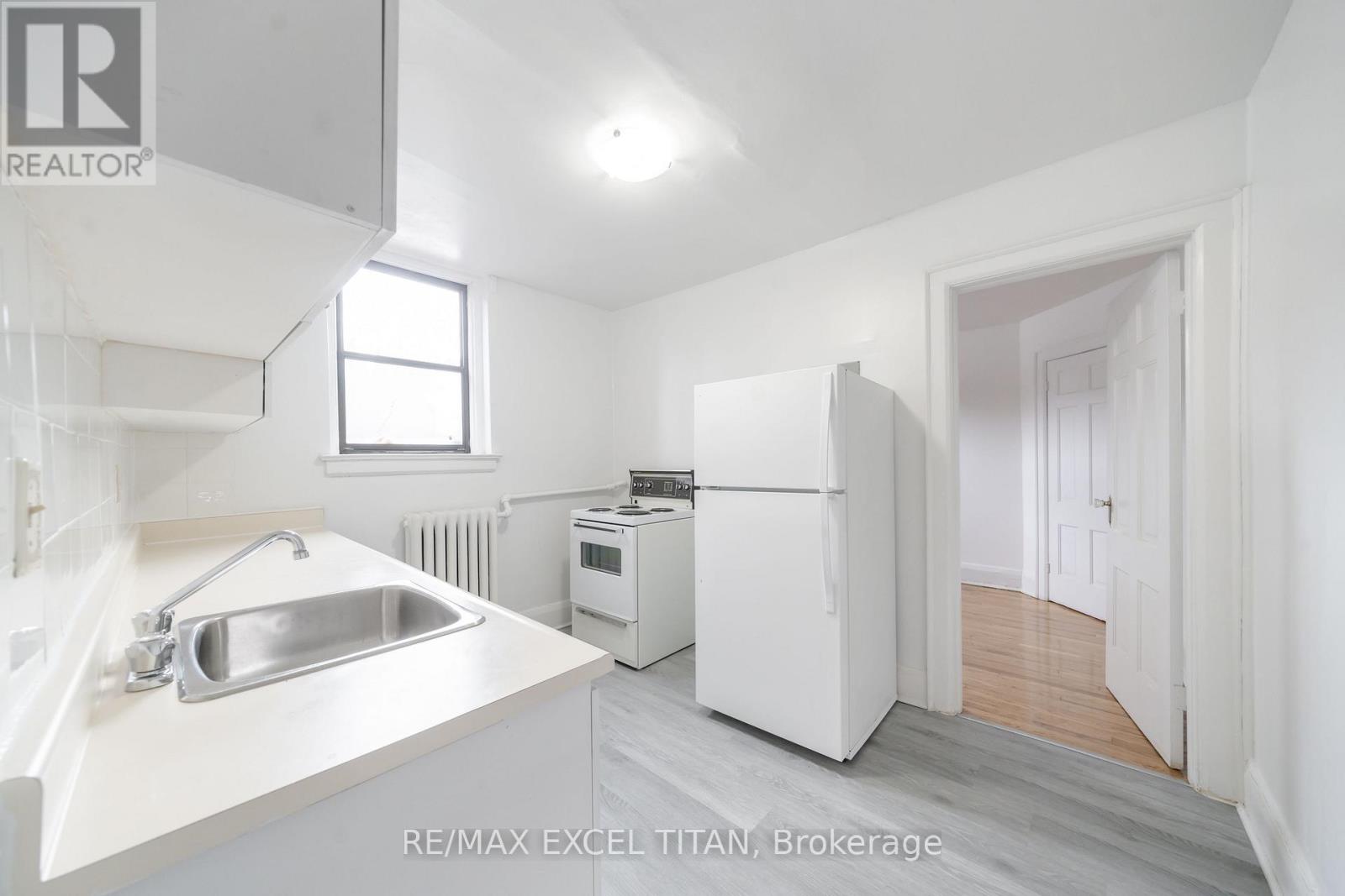 A white kitchen with a sink and a refrigerator.