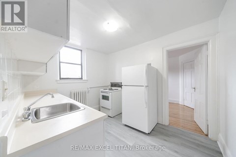 A white kitchen with a sink and a refrigerator.