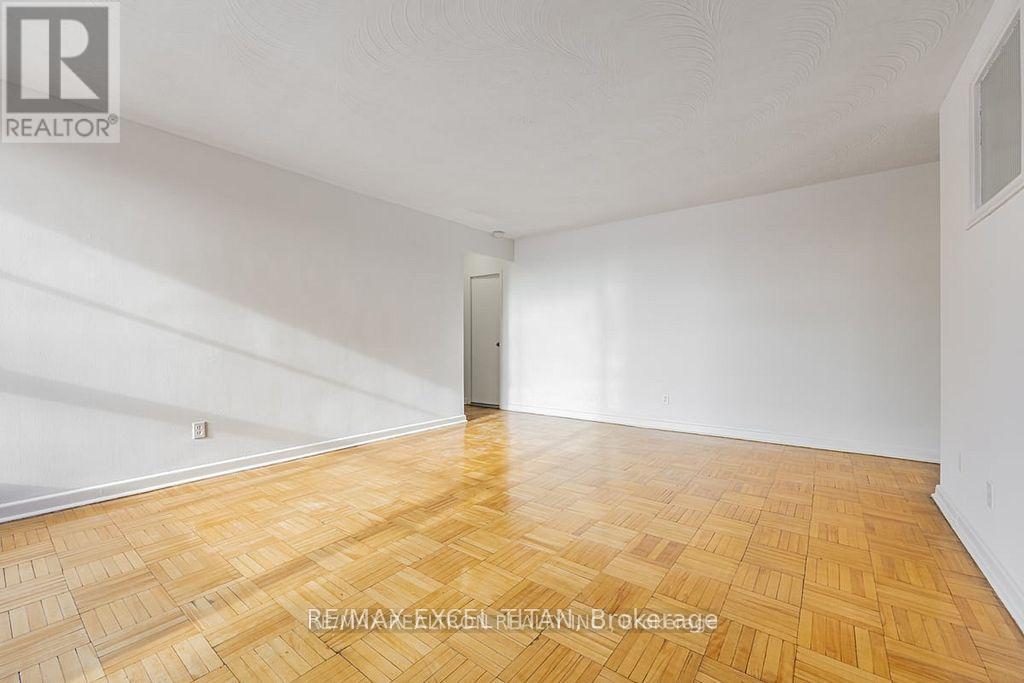 A room with wooden flooring and white walls, with a door in the background.