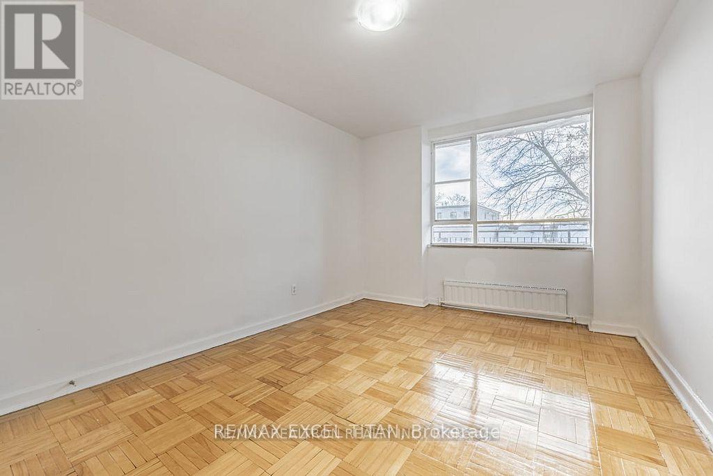 A room with a wooden floor and a window showing a tree outside.