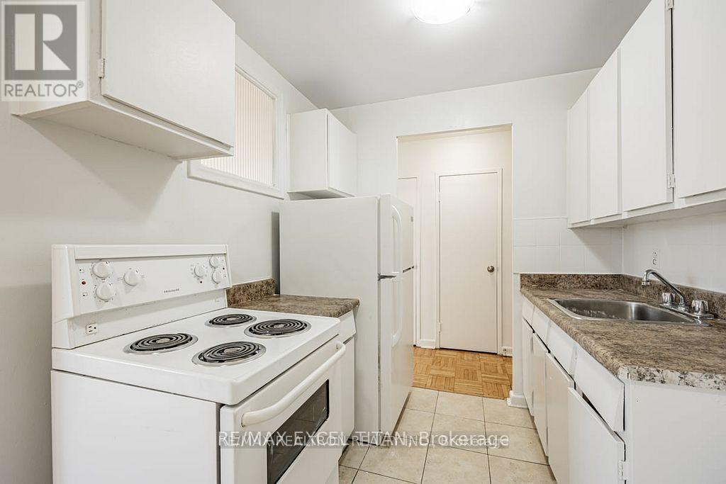 A white kitchen with a stove, sink, and cabinets.