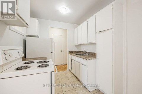A white kitchen with a stove top oven and a sink.