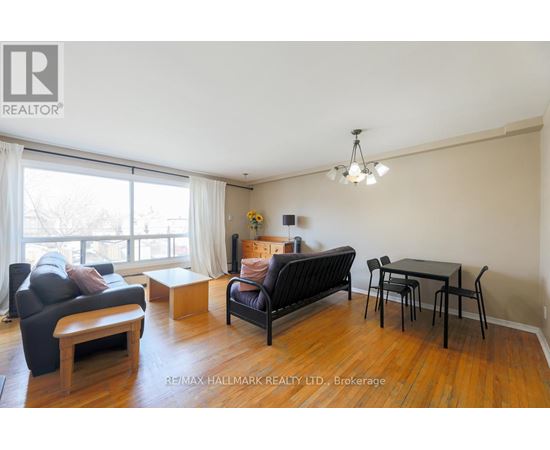 A living room with a black couch, a wooden coffee table, and a dining table with chairs.