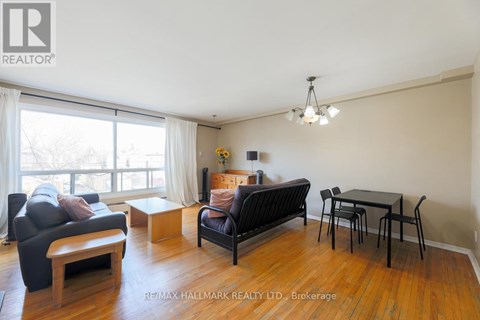 A living room with a black couch, a wooden coffee table, and a dining table with chairs.