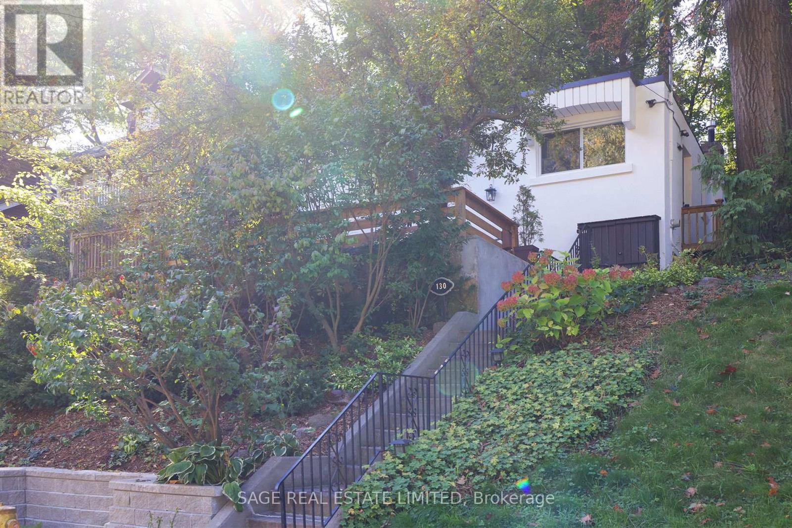 A house with a staircase in front of it is surrounded by trees.