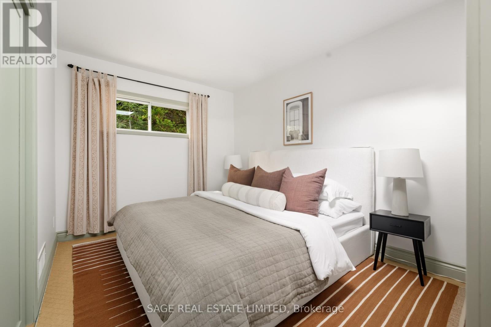 A bedroom with a large bed and a window with curtains.