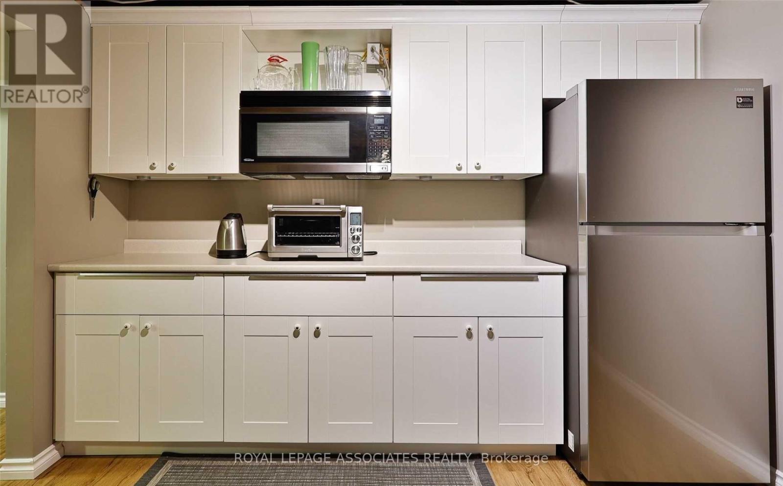 A kitchen with white cabinets and a refrigerator.