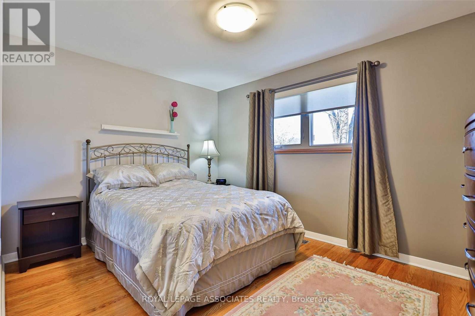 A bedroom with a bed, nightstand, and window.