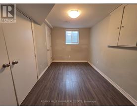 A room with wooden flooring and a window with blinds.