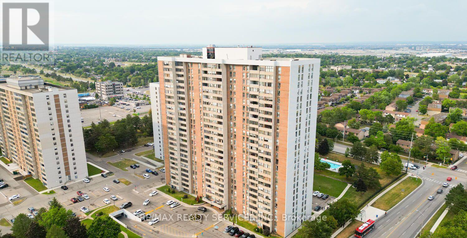 A tall residential building with a parking lot in front.