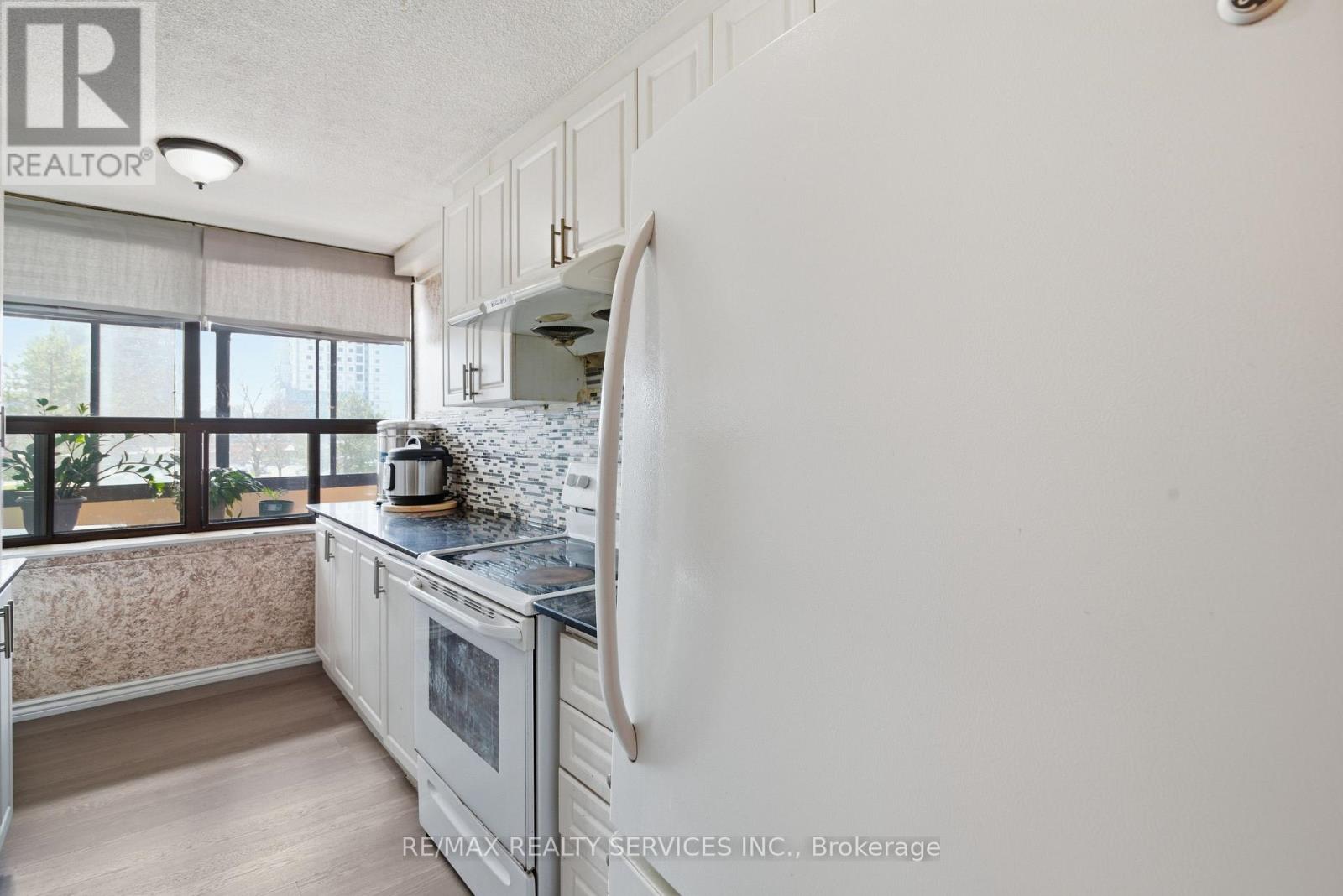 A kitchen with white cabinets and a marble countertop.