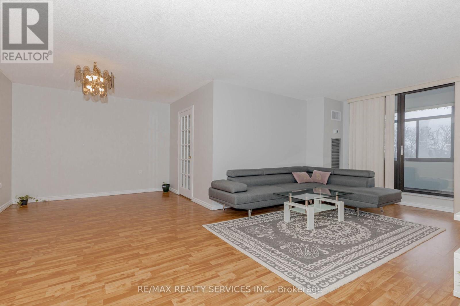 A living room with a grey couch and a chandelier.