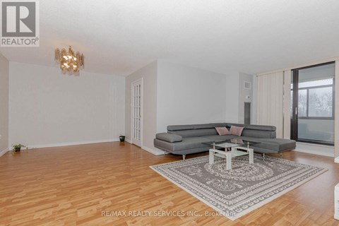A living room with a grey couch and a chandelier.
